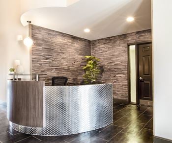 A curved reception desk in a hotel lobby with a brick wall